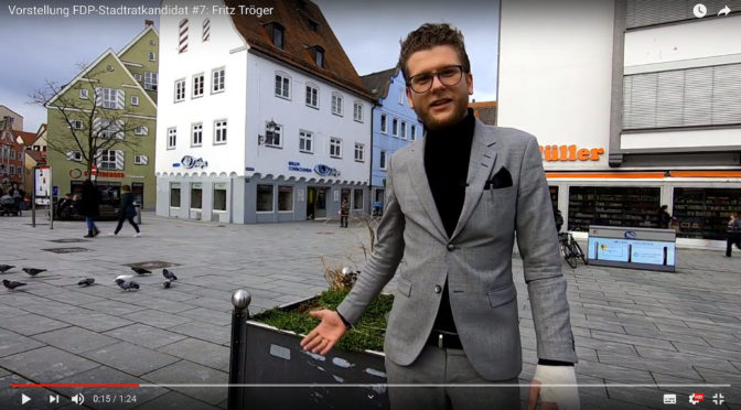 Vor seinem Optikergeschäft￼￼ in der Memminger Innenstadt stellt sich der Jungunternehmer Fritz Tröger als Stadtratskandidat der FDP vor. (Screenshot Youtube)